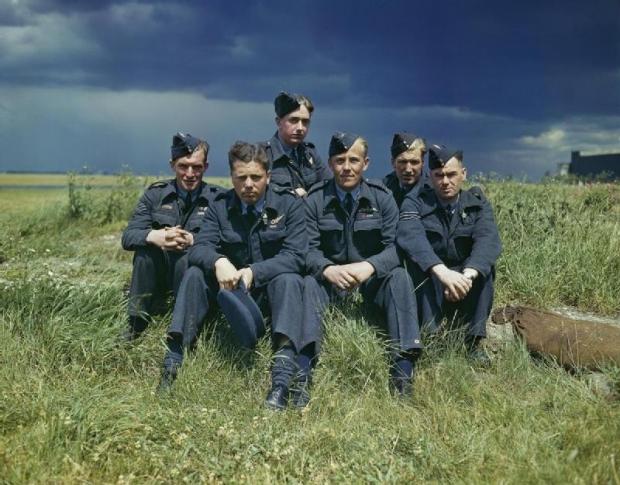 The Northern Echo: 617 Squadron (Dambusters) at Scampton, Lincolnshire, 22 July 1943. Object description: The crew of Lancaster ED285/'AJ-T' sitting on the grass, posed under stormy clouds. Left to right: Sergeant G Johnson; Pilot Officer D A MacLean, navigator;